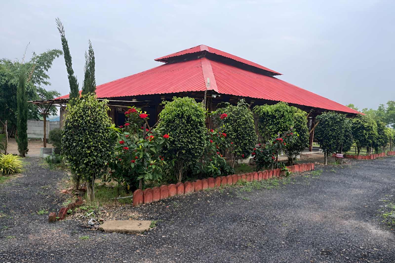 Conference hall wide exterior view — bamboo columns and red metal roof at Pench Tiger Resort